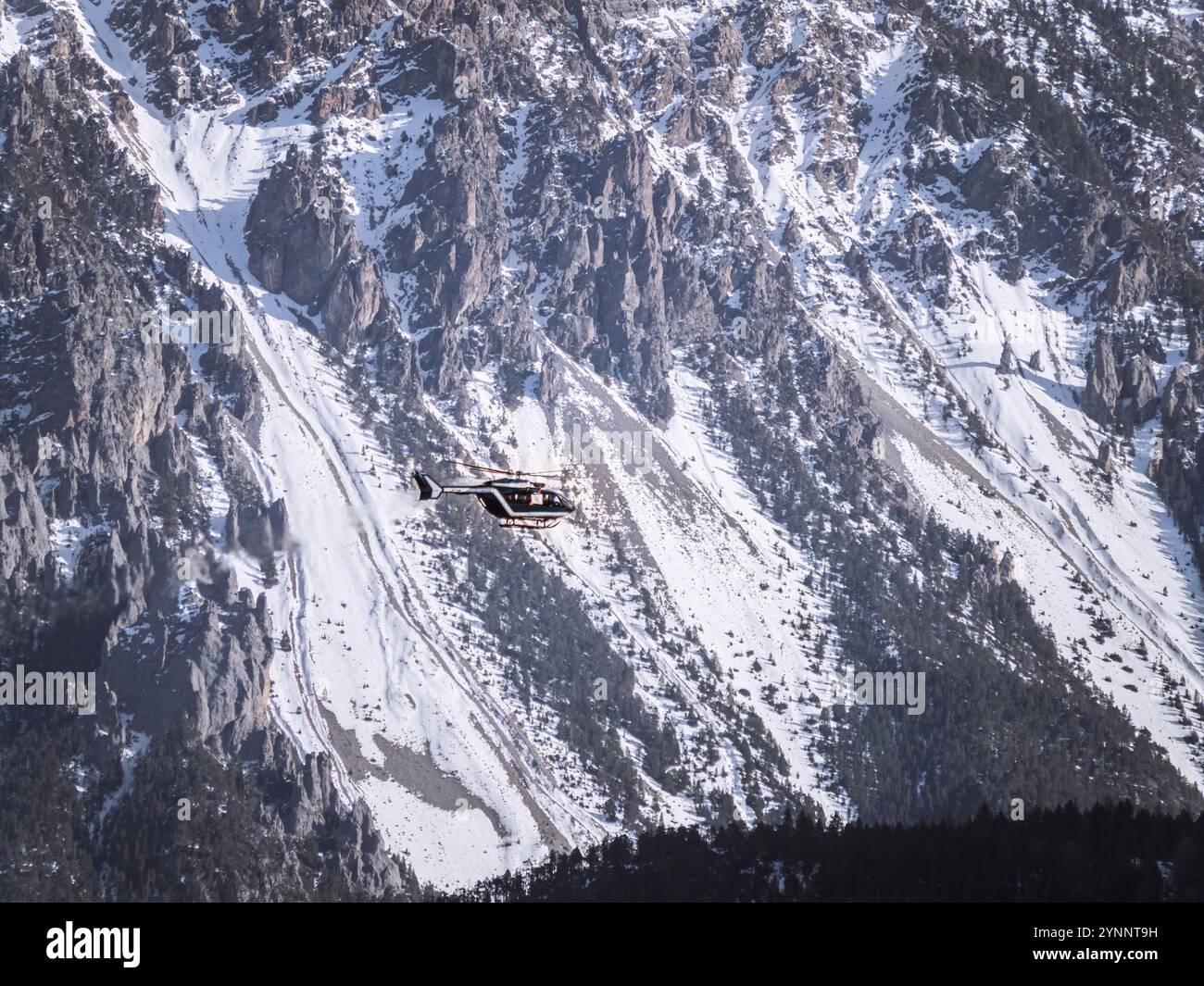 Un hélicoptère de sauvetage vole près de pics abrupts et enneigés à serre Chevalier, Briançon dans les Alpes françaises le paysage alpin spectaculaire met en évidence la falaise Banque D'Images