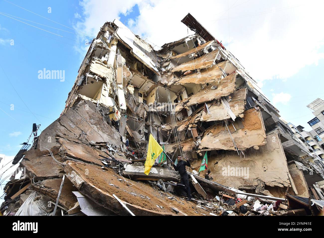 Beyrouth, Liban. 26 novembre 2024. Un drapeau de Man cary du Hezbollah sur des bâtiments détruits sur le site d'une frappe aérienne israélienne de nuit qui a ciblé la zone de Tayouneh à la périphérie de la banlieue sud de Beyrouth, au Liban, mardi 26 novembre 2024. De vastes frappes aériennes israéliennes ont frappé Beyrouth, sa banlieue et d'autres régions du Liban en prévision d'un cessez-le-feu attendu pour mettre fin à la guerre entre le Hezbollah et Israël. Photo de Rahim Rhea/UPI. Crédit : UPI/Alamy Live News Banque D'Images
