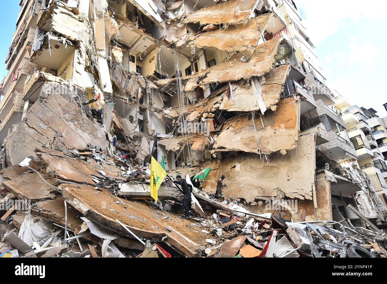 Beyrouth, Liban. 26 novembre 2024. Un drapeau de Man cary du Hezbollah sur des bâtiments détruits sur le site d'une frappe aérienne israélienne de nuit qui a ciblé la zone de Tayouneh à la périphérie de la banlieue sud de Beyrouth, libanaise, mardi 26 novembre 2024. De vastes frappes aériennes israéliennes ont frappé Beyrouth, sa banlieue et d'autres régions du Liban en prévision d'un cessez-le-feu attendu pour mettre fin à la guerre entre le Hezbollah et Israël. Photo de Rahim Rhea/UPI. Crédit : UPI/Alamy Live News Banque D'Images