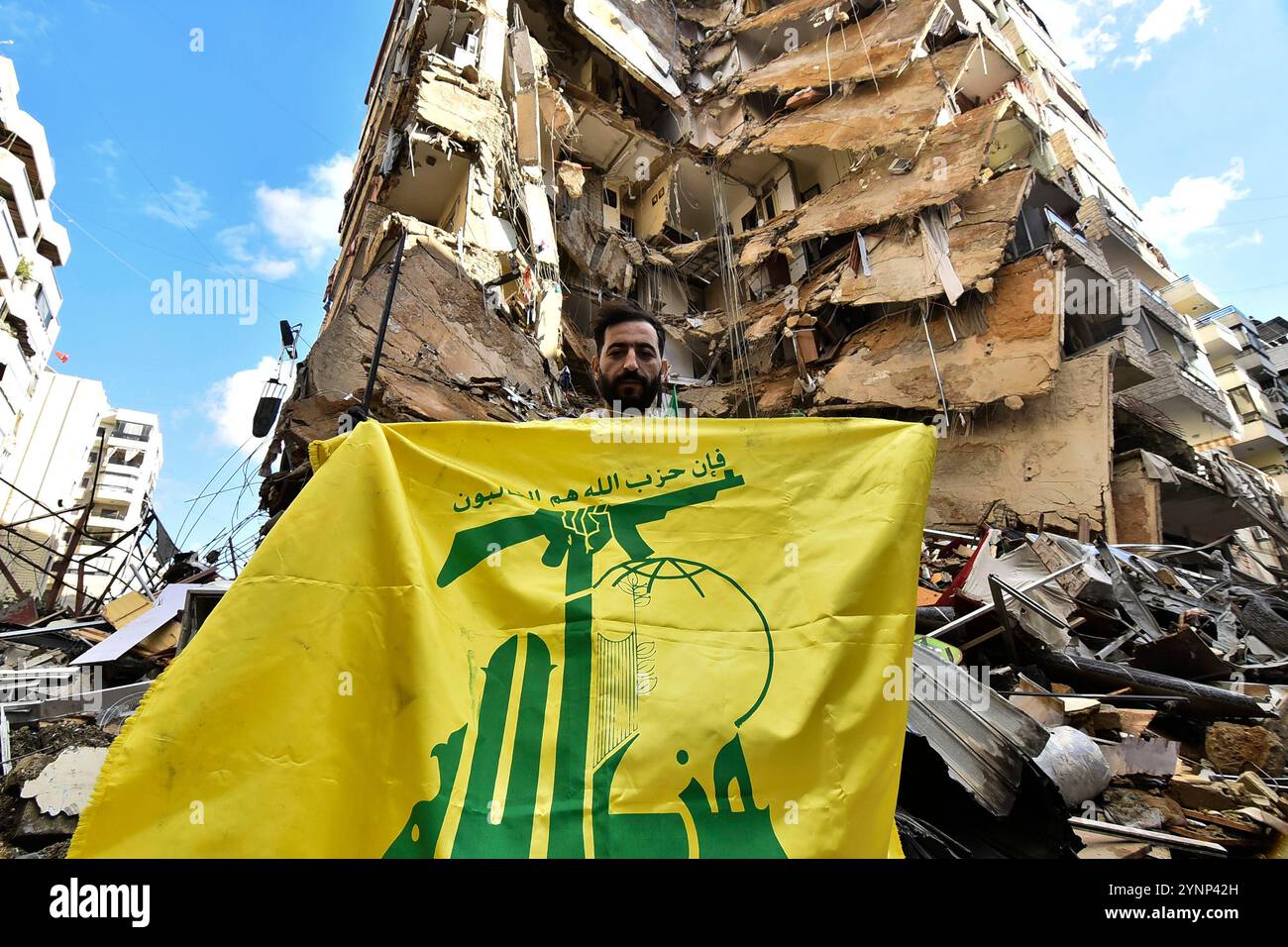 Beyrouth, Liban. 26 novembre 2024. Un drapeau de Man cary du Hezbollah sur des bâtiments détruits sur le site d'une frappe aérienne israélienne de nuit qui a ciblé la zone de Tayouneh à la périphérie de la banlieue sud de Beyrouth, libanaise, mardi 26 novembre 2024. De vastes frappes aériennes israéliennes ont frappé Beyrouth, sa banlieue et d'autres régions du Liban en prévision d'un cessez-le-feu attendu pour mettre fin à la guerre entre le Hezbollah et Israël. Photo de Rahim Rhea/UPI. Crédit : UPI/Alamy Live News Banque D'Images