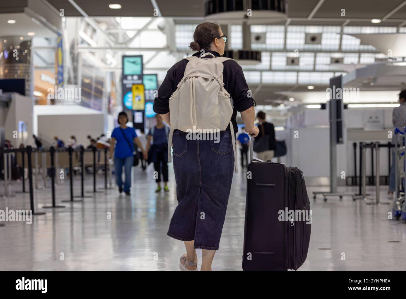 Voyageur avec un sac à dos et une valise dans un terminal d'aéroport très fréquenté Banque D'Images