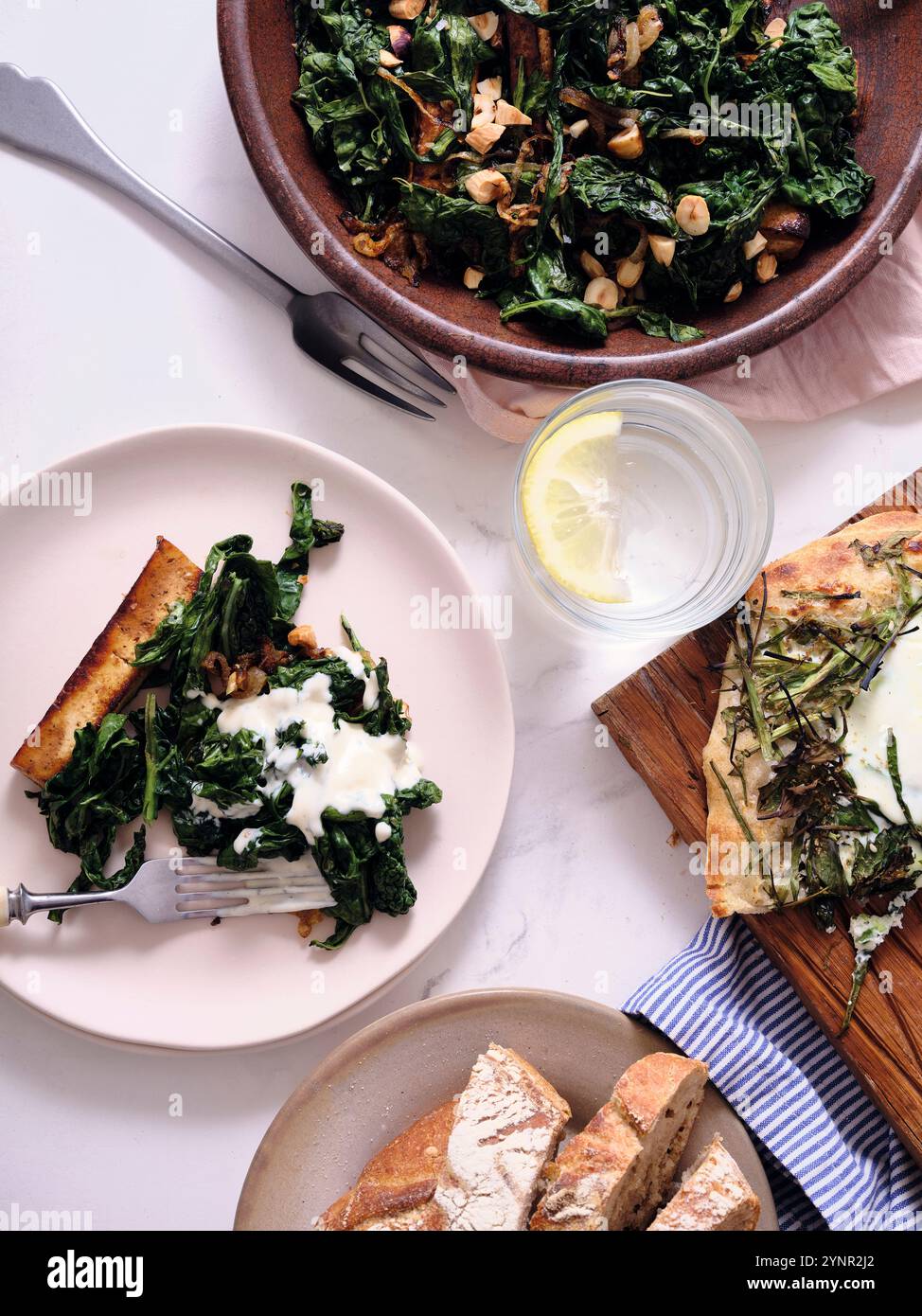 Dîner sain composé d'ingrédients de saison : tofu avec chou frisé, fenouil et salade de pommes, pois mange-tout cuits à la vapeur, poisson rôti et pain au levain. Banque D'Images