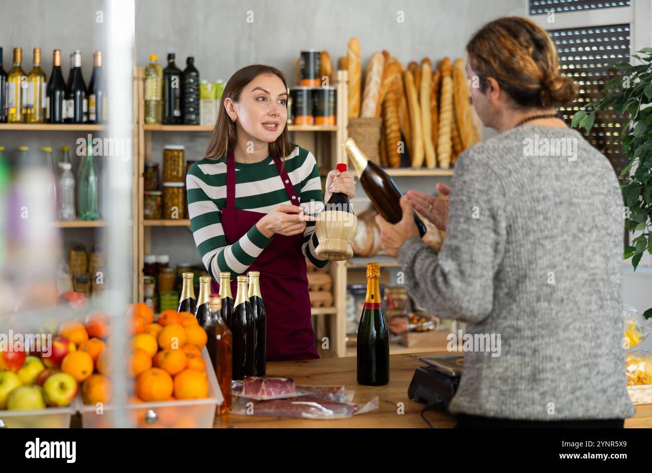 Le vendeur féminin propose à l'homme d'acheter de l'alcool dans le supermarché Banque D'Images
