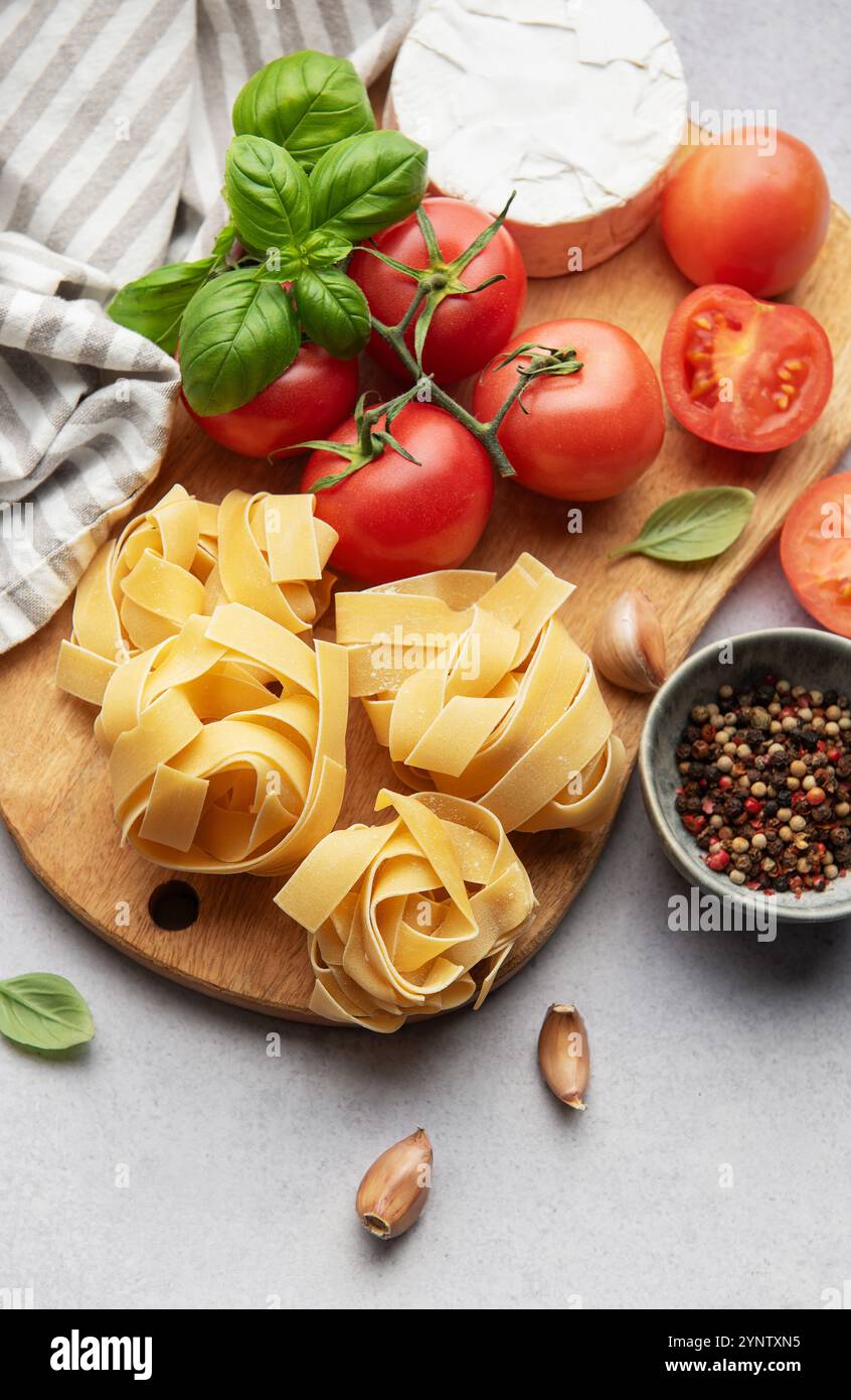 Ingrédients frais disposés sur une planche à découper en bois, prêts à préparer un plat de pâtes Banque D'Images