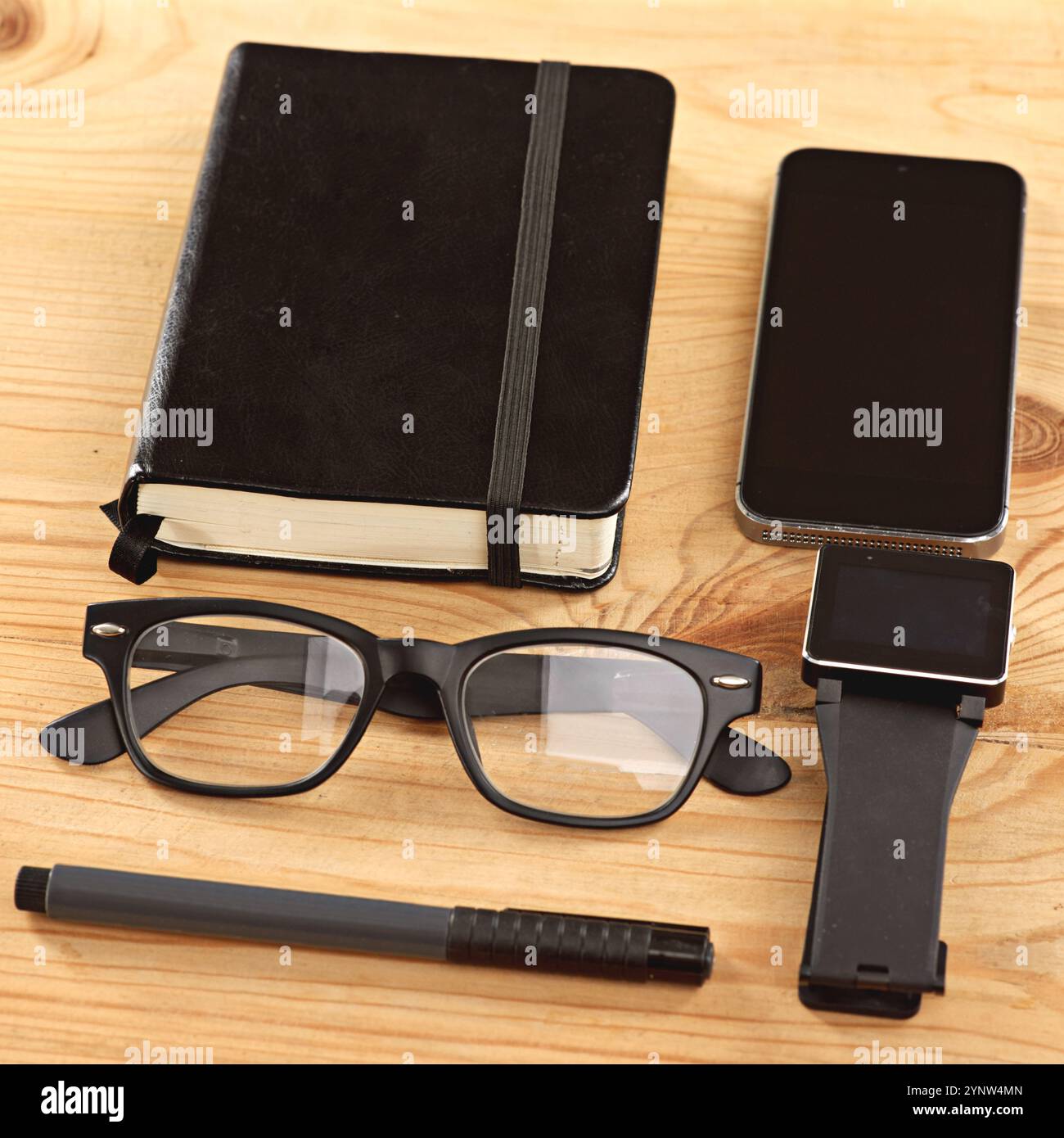 Téléphone, montre et lunettes sur le bureau en bois avec carnet, stylo et journal gros plan dans le bureau pour les affaires. Technologie, livres et écran mobile sur table Banque D'Images