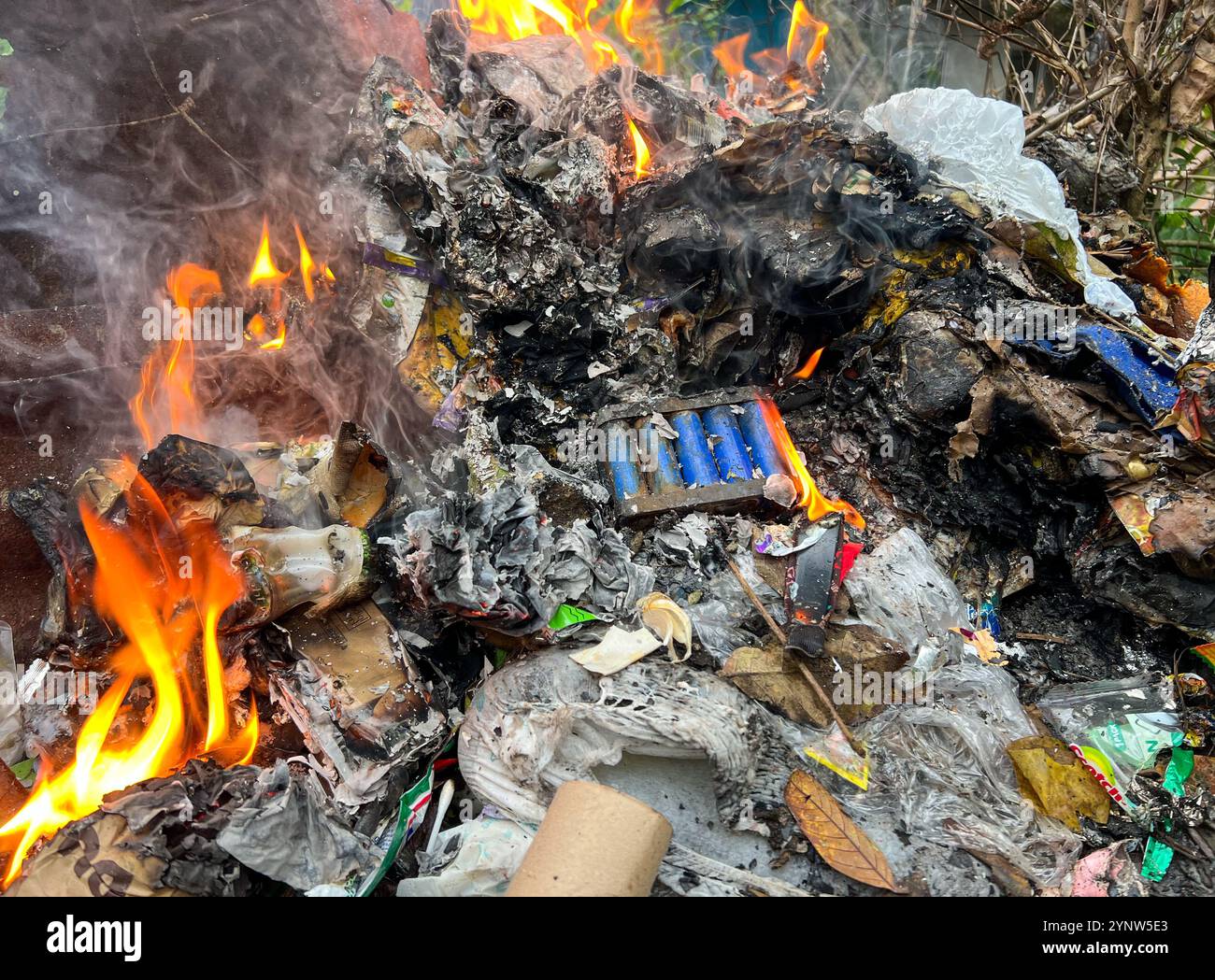 Philippines problème de pollution : déchets plastiques fondus et E, électronique brûlés parmi les ordures ménagères, batterie au lithium en feu, décharge technologique, décharge - Image de stock capturée avec un smartphone