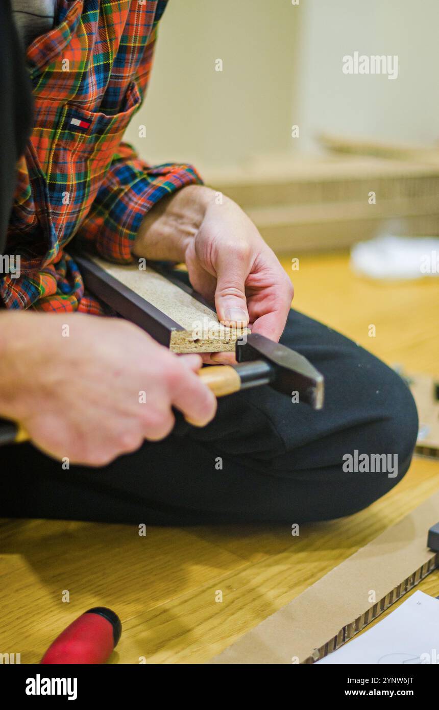 Instruction d'assemblage de Hummer de maintien masculin sur plancher en bois pour la configuration de meubles de bricolage. Photo de haute qualité Banque D'Images