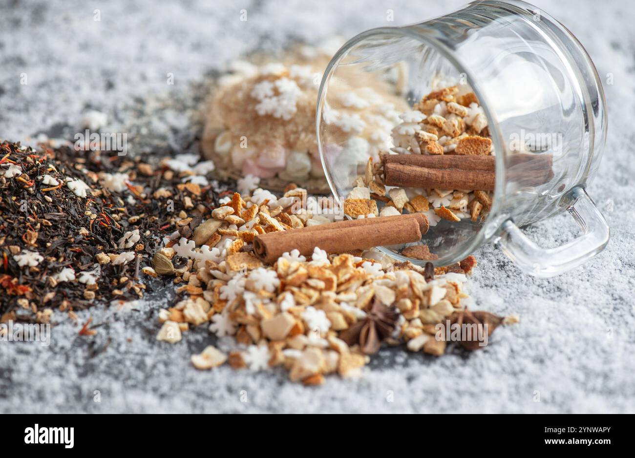 ingrédient de boisson chaude d'hiver renversé avec des épices, en forme d'étoile et de sucre et de tasse de verre retournent sur fond neigeux Banque D'Images