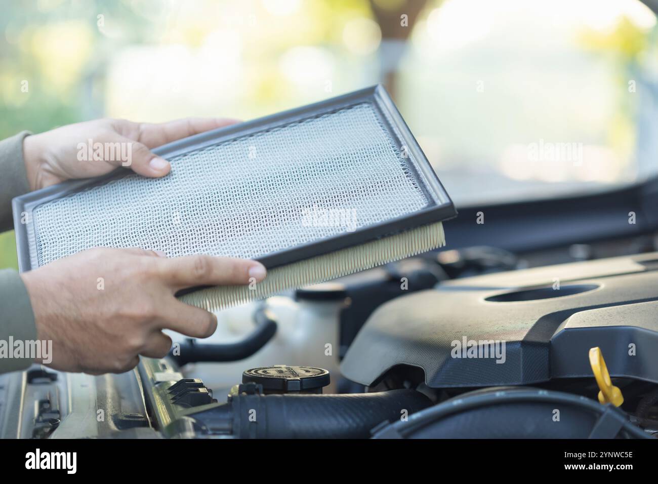 Un propriétaire de voiture tient un filtre à air pour examen. Importance de l'inspection régulière, le nettoyage et le remplacement des filtres à air de voiture, souligne maintenanc Banque D'Images