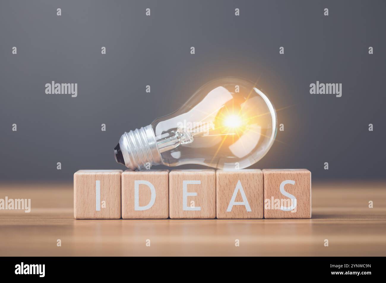 Une ampoule à côté des lettres en bois orthographiant «IDÉES» disposées sur une table symbolise l'étincelle des nouvelles idées et de la créativité. Cette image reflète inspira Banque D'Images