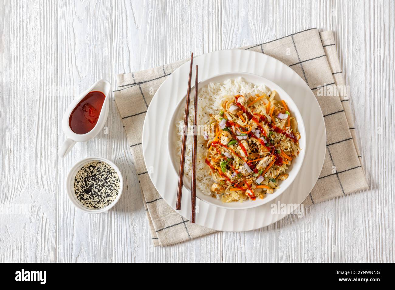 roulé aux œufs de tofu, chou sautés, tofu émietté assaisonné servi dans une sauce sucrée et salée servie sur du riz dans un bol sur une table en bois blanc avec des côtelettes Banque D'Images