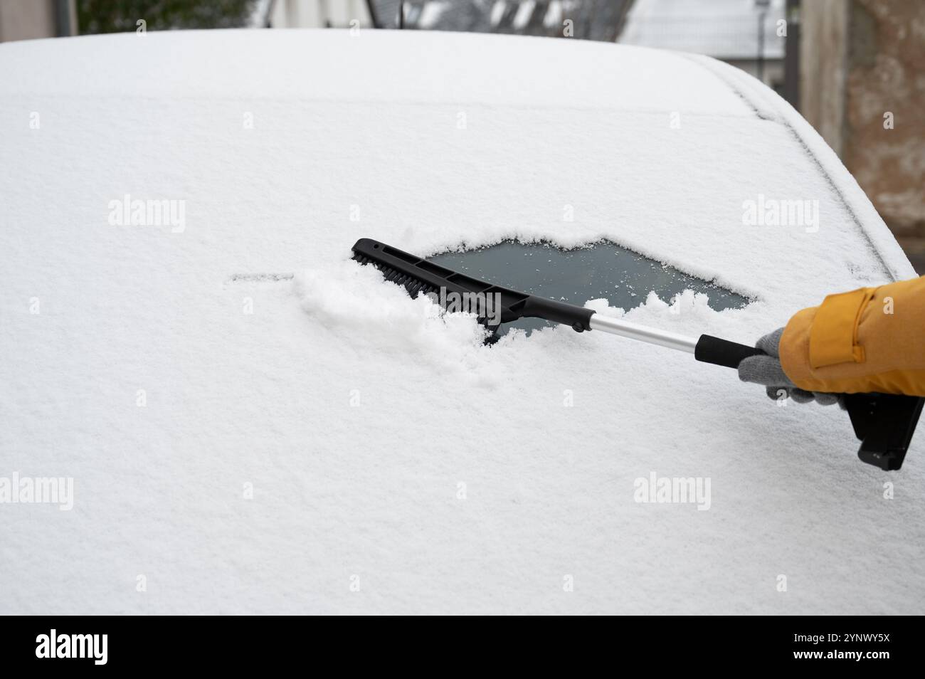 Le conducteur enlève la neige du pare-brise de la voiture avec grattoir à glace et balai, nettoyer la fenêtre de la voiture du gel glacé, saison d'hiver Banque D'Images