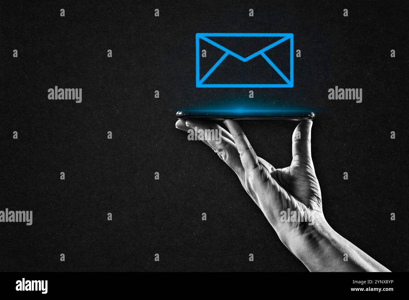 Main en noir et blanc tenant smartphone avec Blue Email Sign sur fond de papier texturé, espace de copie Banque D'Images