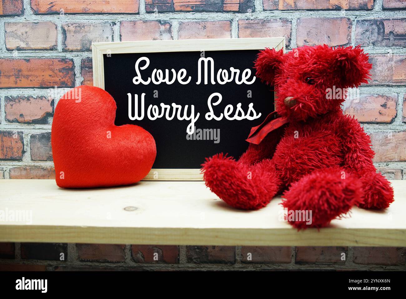 Love More Worry Less Motivational and inspiration citations sur tableau noir avec ours en peluche sur fond en bois Banque D'Images