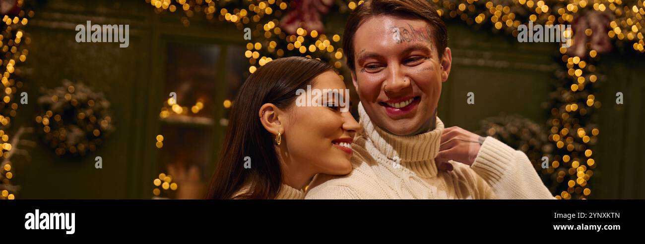 Un couple aimant se sourit tout en étant entouré de lumières scintillantes et d'un décor de vacances. Banque D'Images