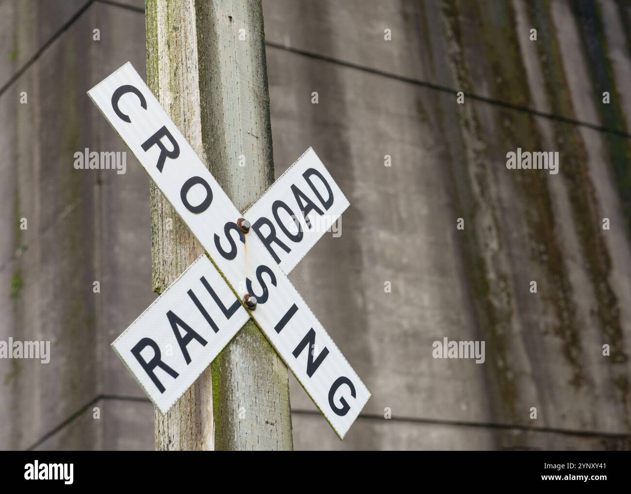 Gros plan d'un panneau Railroad Crossing devant un mur d'aspect industriel grungy, États-Unis Banque D'Images