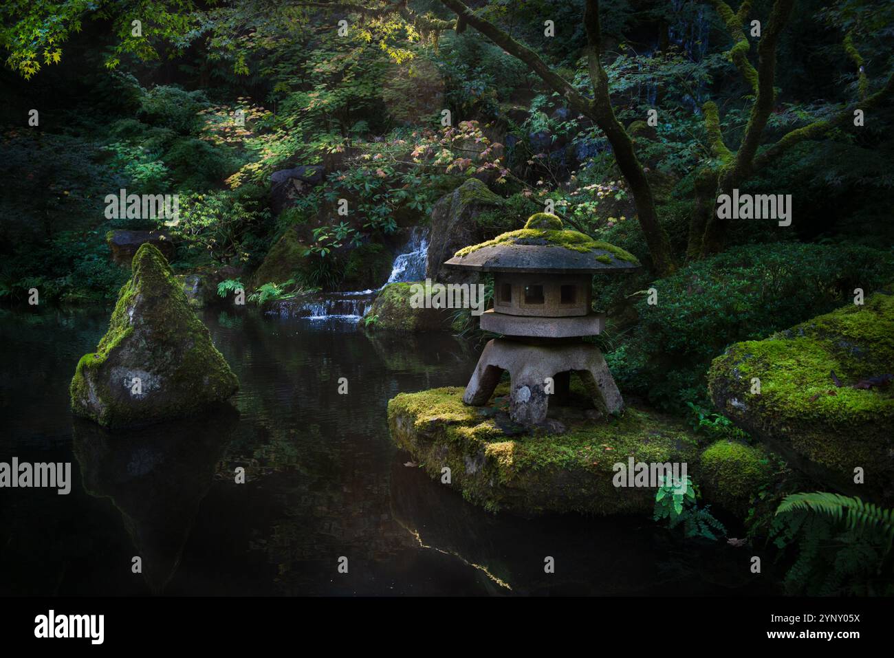 Gros plan d'un ornement de lanterne dans un jardin luxuriant japonais avec une cascade, États-Unis Banque D'Images