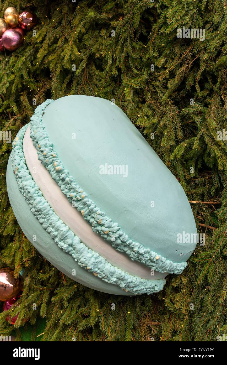 La décoration originale sous la forme d'un macaron géant sur le mur extérieur, recouvert de branches de sapin, crée une atmosphère festive de Noël. Banque D'Images