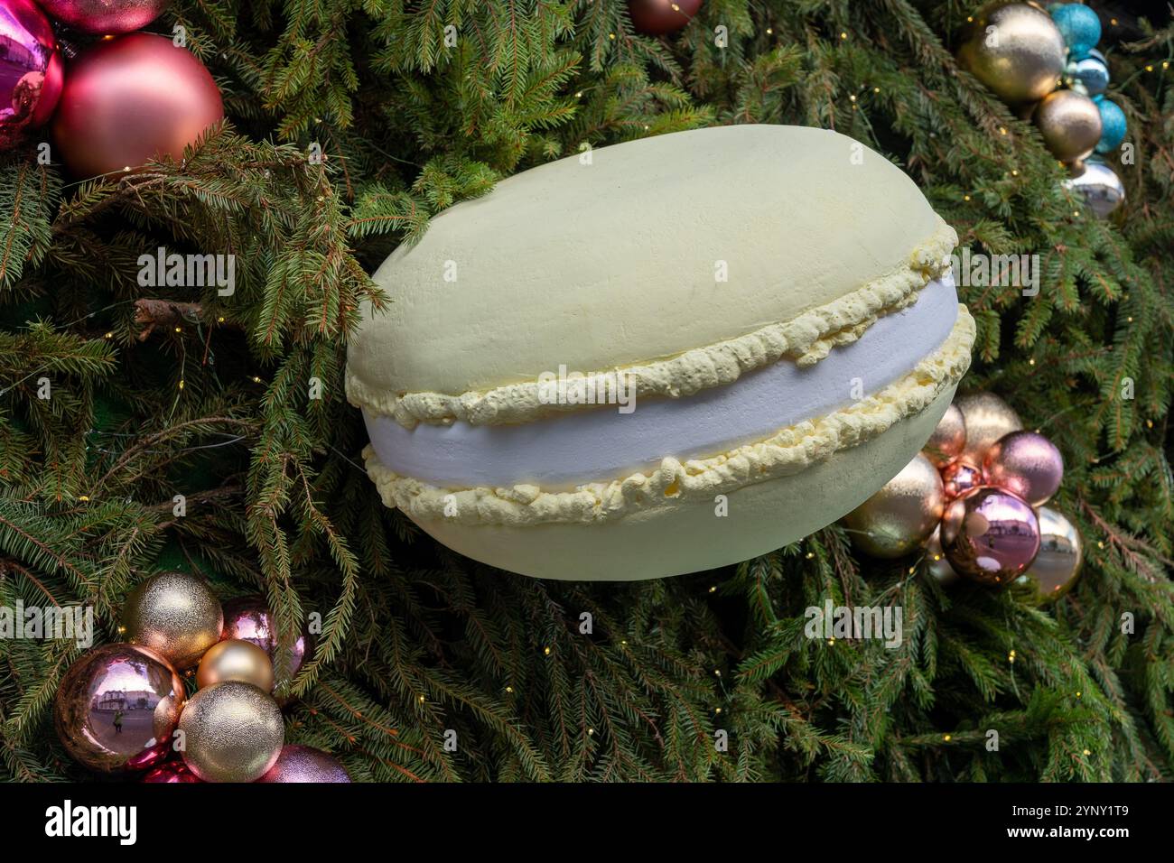 La décoration originale sous la forme d'un macaron géant sur le mur extérieur, recouvert de branches de sapin, crée une atmosphère festive de Noël. Banque D'Images