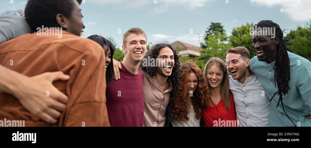 Jeunes membres de l'équipe diversifiés se joignant la main dans le cercle de l'unité à l'extérieur. Moment authentique montrant un groupe d'ethnicité mixte faisant preuve de travail d'équipe et d'inclusion. Banque D'Images