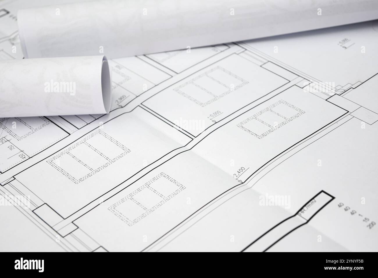 Les plans roulés reposent sur des plans de maison dépliés, mettant en valeur des mesures précises et des détails architecturaux. Banque D'Images