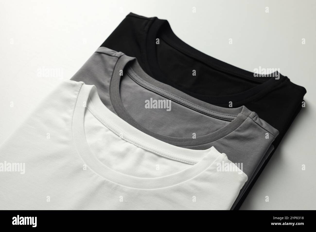Différents t-shirts vierges sur fond blanc, gros plan. Maquette pour le design Banque D'Images Différents t-shirts vierges sur fond blanc, gros plan. Maquette pour le design Banque D'Images