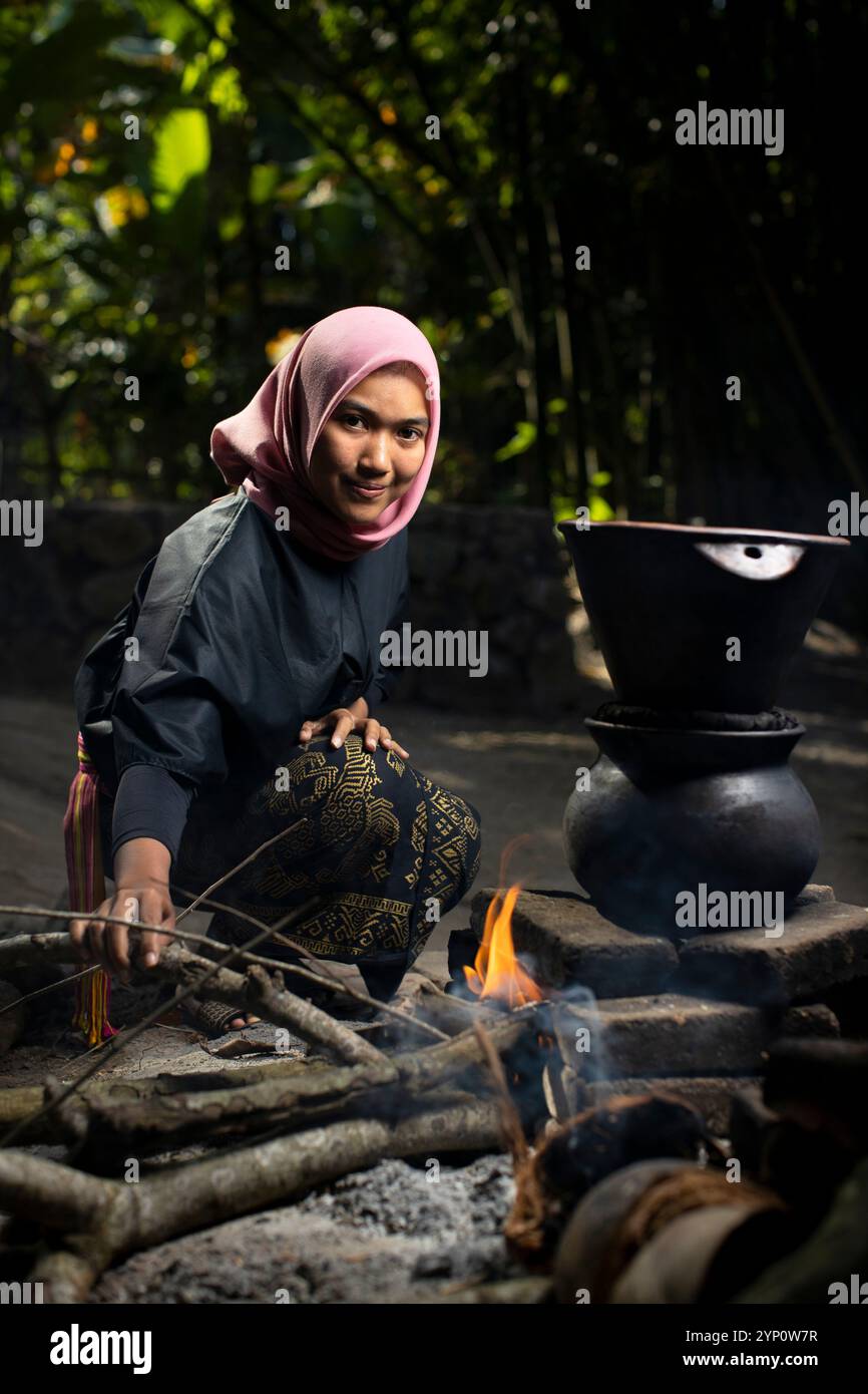 Une femme cuisant du riz à la vapeur selon une méthode de cuisson traditionnelle, Lombok, West Nusa Tenggara, Indonésie. Banque D'Images