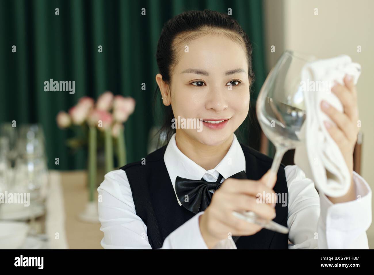 Serveuse souriante qui polit le verre à vin au restaurant Banque D'Images