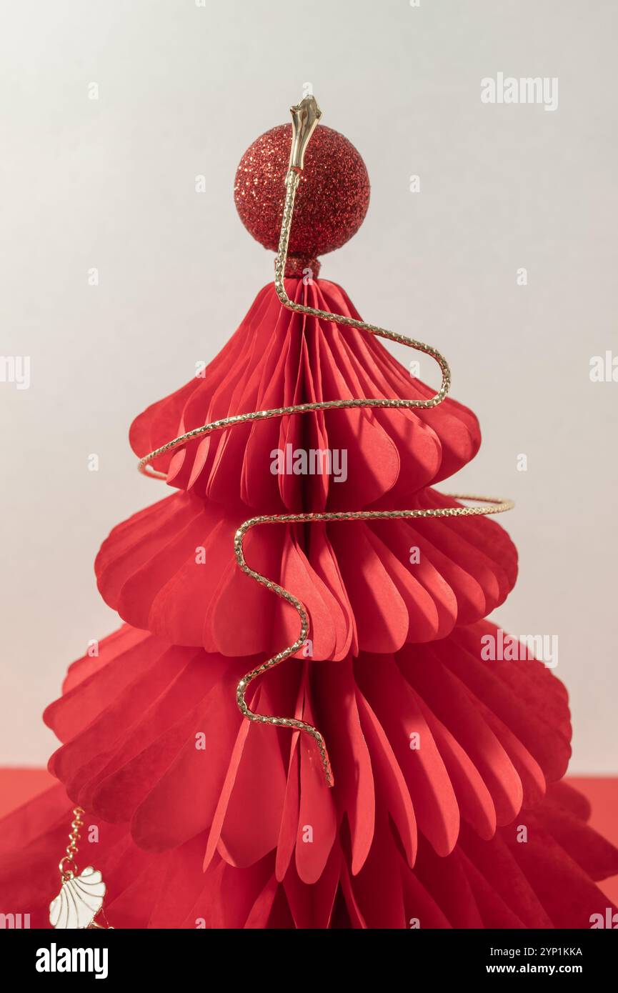 Collier de chane doré sur un arbre en nid d'abeille de Noël en papier rouge. Banque D'Images