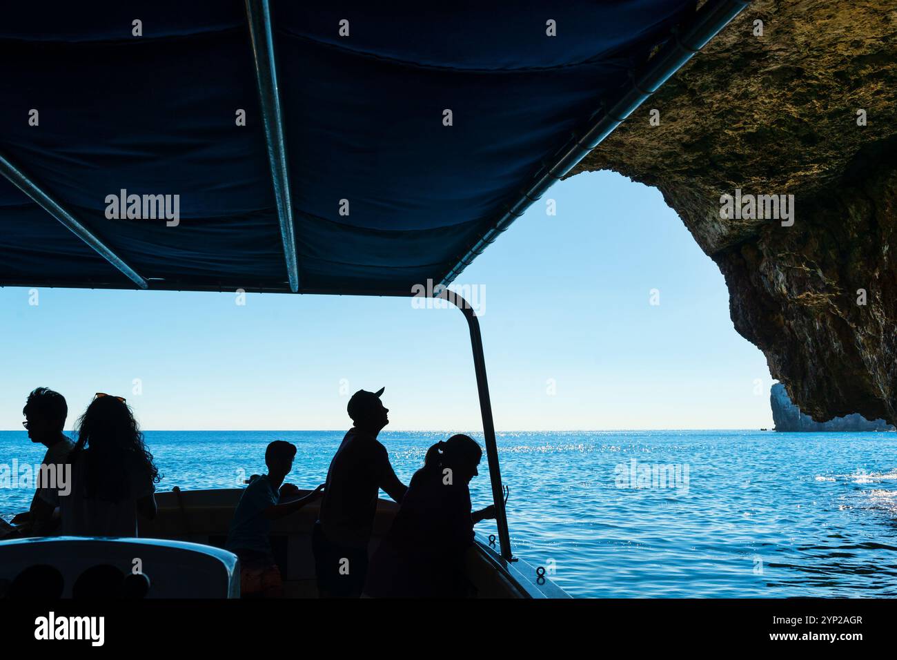 Silhouettes des personnes prenant le tour en bateau autour de la célèbre grotte marine Blue Grotto sur le littoral de Malte Banque D'Images