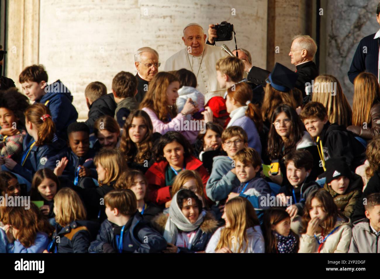 Le Pape François bénit les fidèles lors d'un événement public à la basilique Saint-Pierre entouré d'enfants et du clergé symbolisant la foi espérance et catholique Banque D'Images