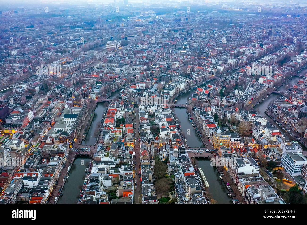 Vue aérienne du quartier emblématique des canaux d'Amsterdam au crépuscule, avec toits vibrants, rues illuminées et architecture historique, capturant t Banque D'Images