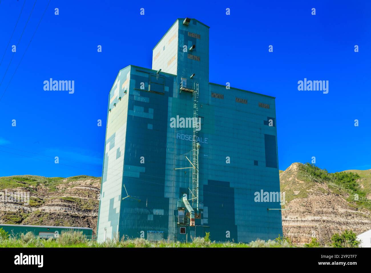 Un grand silo à grain ancien avec un toit bleu. Le bâtiment est vide et a une apparence altérée Banque D'Images
