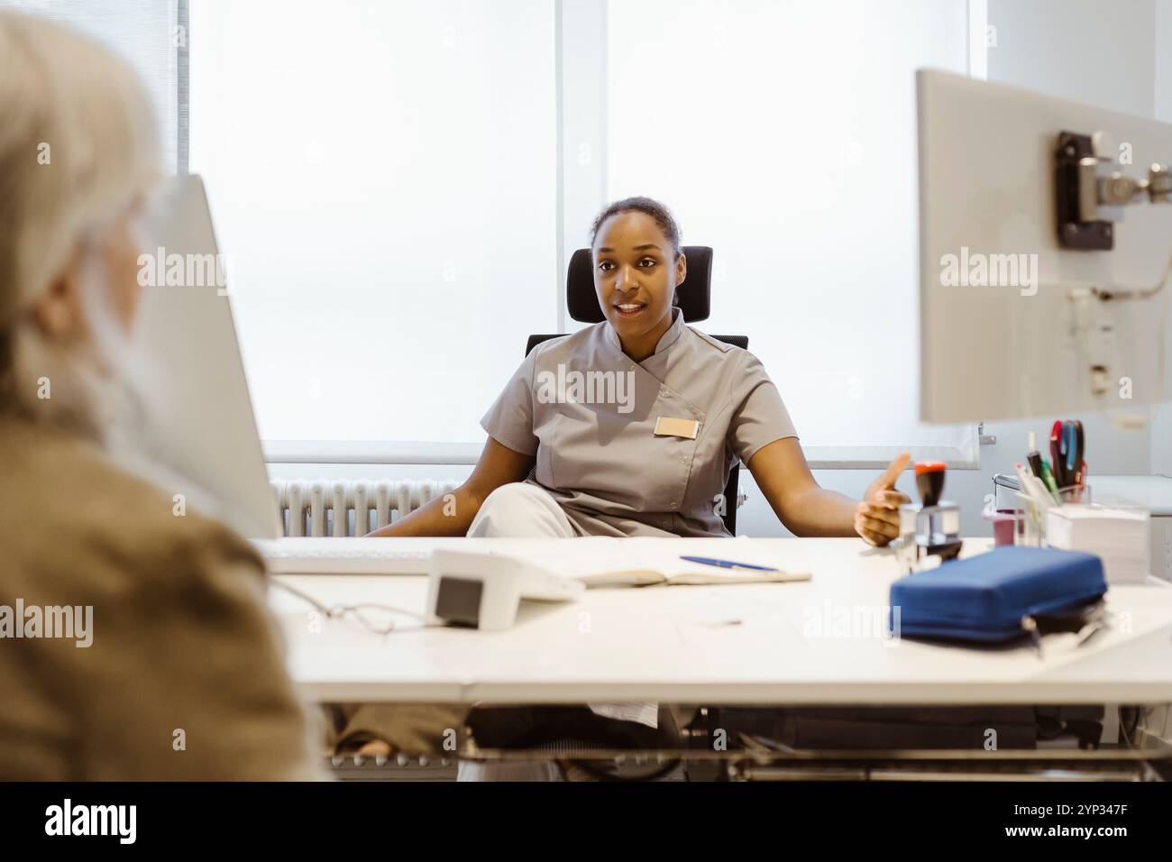 Médecin praticien féminin parlant avec un patient en clinique à l'hôpital Banque D'Images