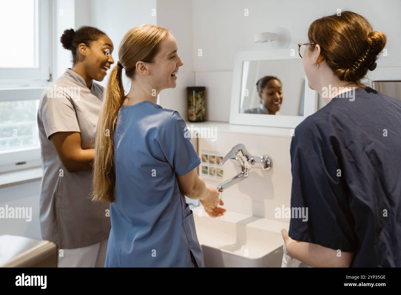 Heureuse équipe médicale féminine parlant entre eux tout en se lavant les mains à l'hôpital Banque D'Images