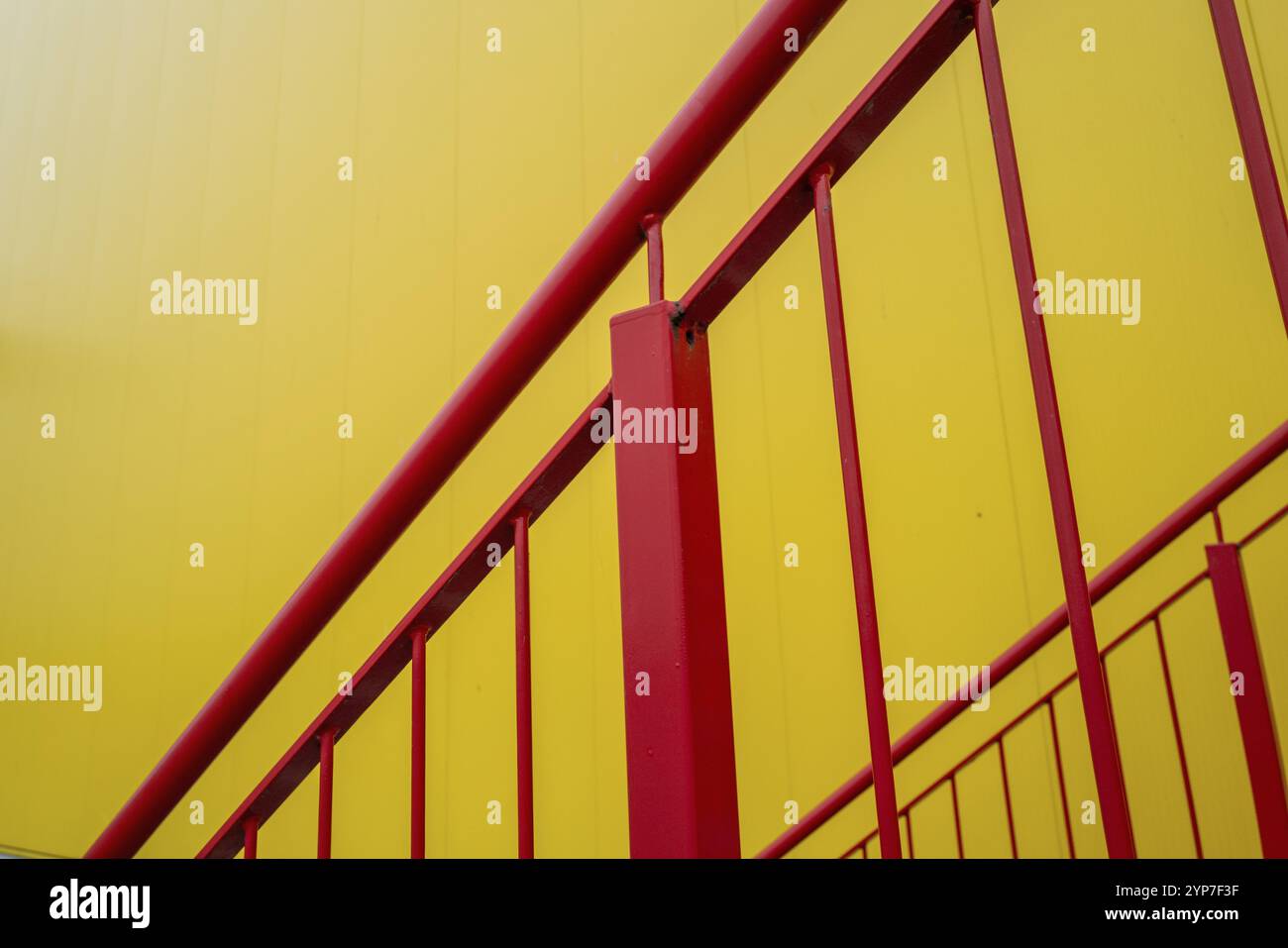 Escalier d'échappement rouge à l'extérieur de l'escalier sur le bâtiment industriel de mur jaune Banque D'Images