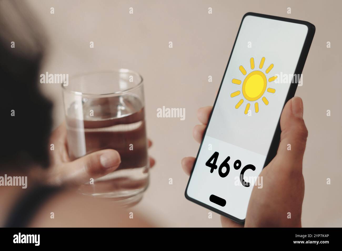 Dans cette illustration photo, une femme tient un verre d'eau, le thermomètre montrant 46ÂºC de chaleur est affiché sur l'écran d'un smartphone Banque D'Images