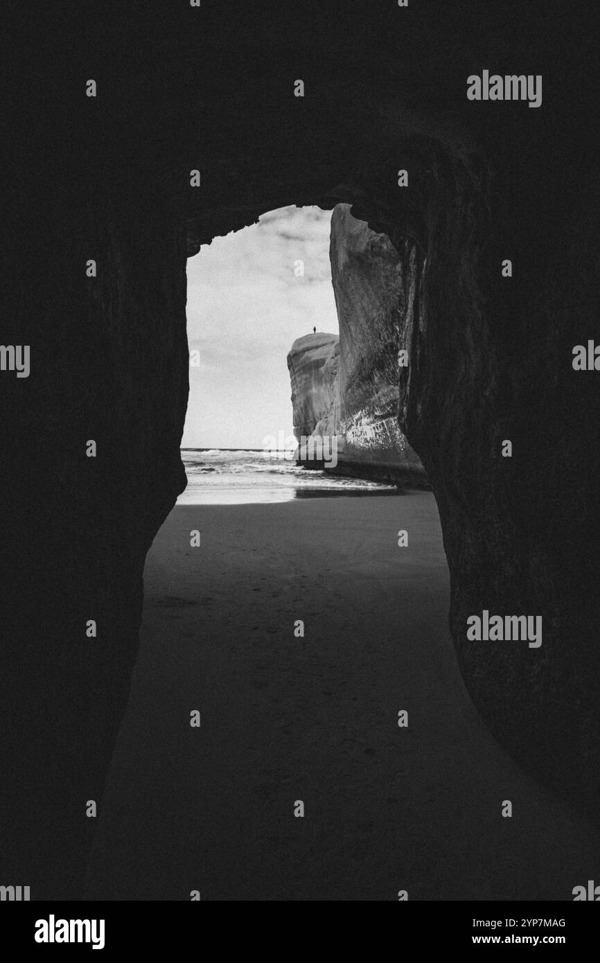 Vue mer par l'entrée d'une grotte sombre en noir et blanc, Dunedin, Nouvelle-Zélande, Océanie Banque D'Images