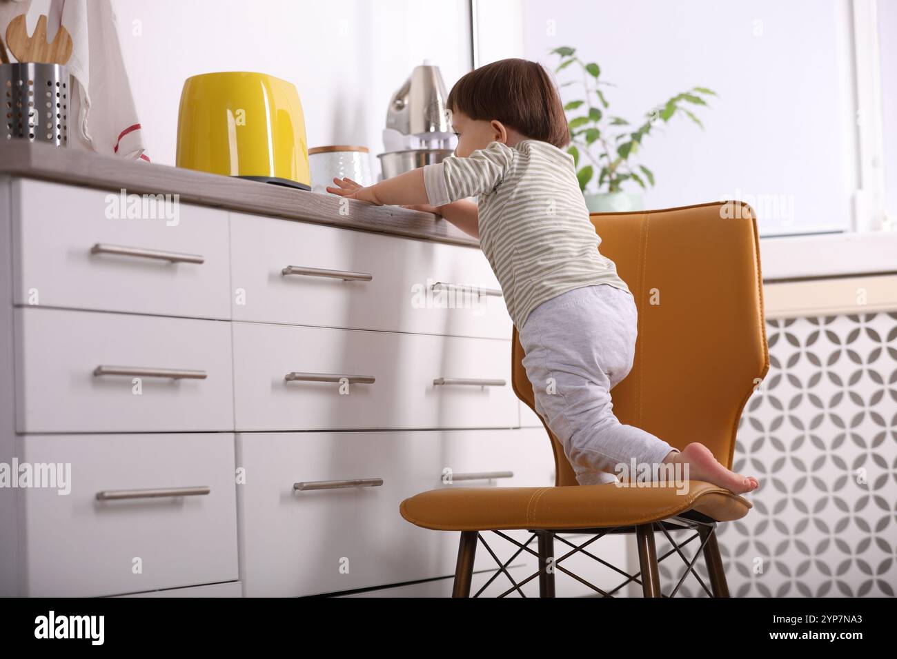 Petit garçon jouant avec le grille-pain dans la cuisine. Situation dangereuse Banque D'Images