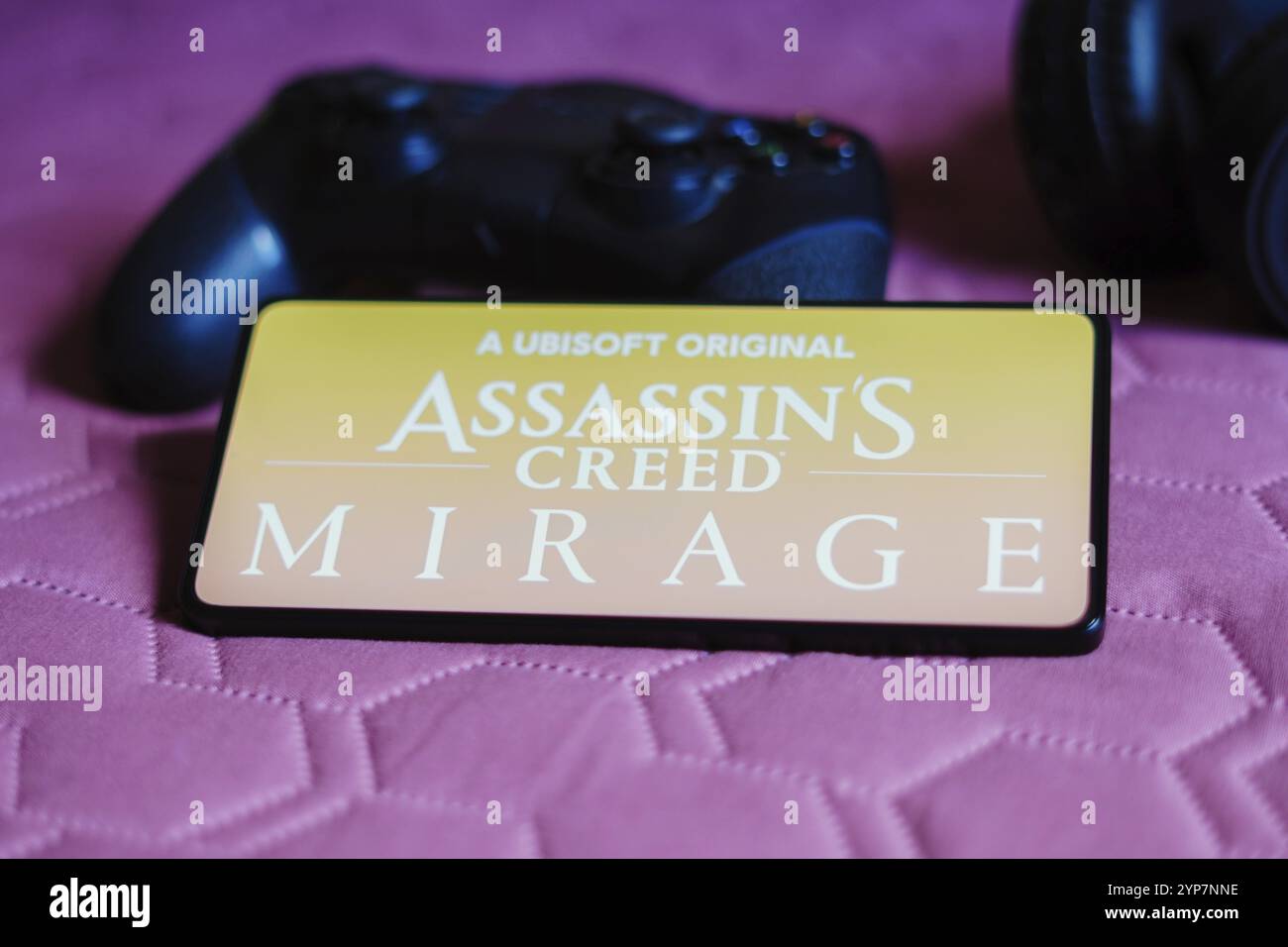 Dans cette illustration photo, le logo Assassin's Creed Mirage est affiché sur l'écran d'un smartphone, à côté d'une manette de jeu Banque D'Images