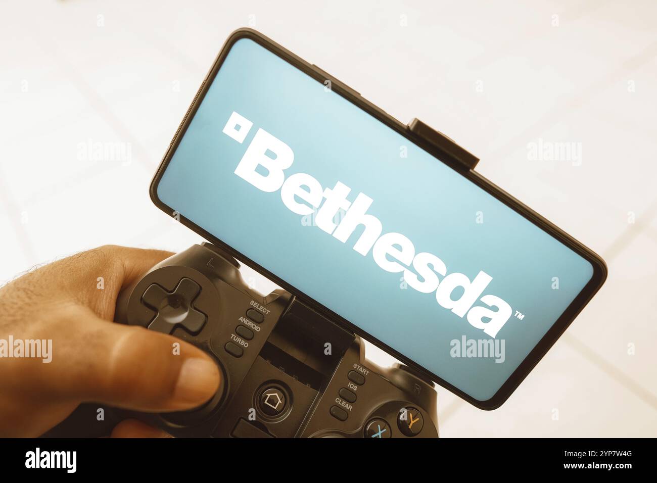 Dans cette illustration photo, une personne joue sur un joystick et le logo Bethesda Softworks est affiché sur un écran de smartphone Banque D'Images Dans cette illustration photo, une personne joue sur un joystick et le logo Bethesda Softworks est affiché sur un écran de smartphone Banque D'Images