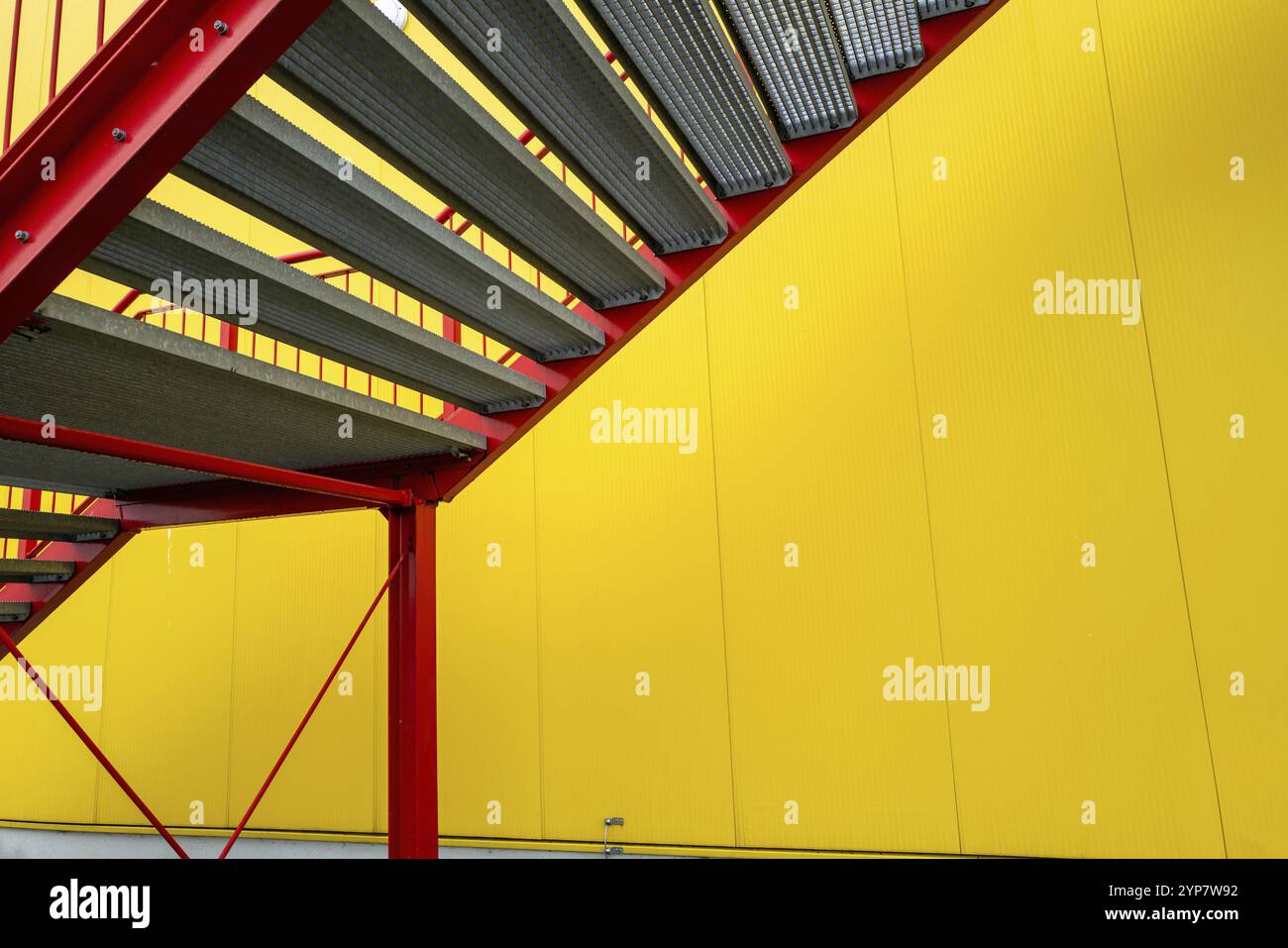 Escalier d'échappement rouge à l'extérieur de l'escalier sur le bâtiment industriel de mur jaune Banque D'Images