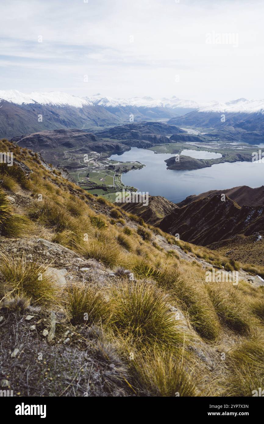 Vue d'un flanc de montagne à une vallée avec un lac au loin, Roys Peak, Wanaka, Nouvelle-Zélande, Océanie Banque D'Images