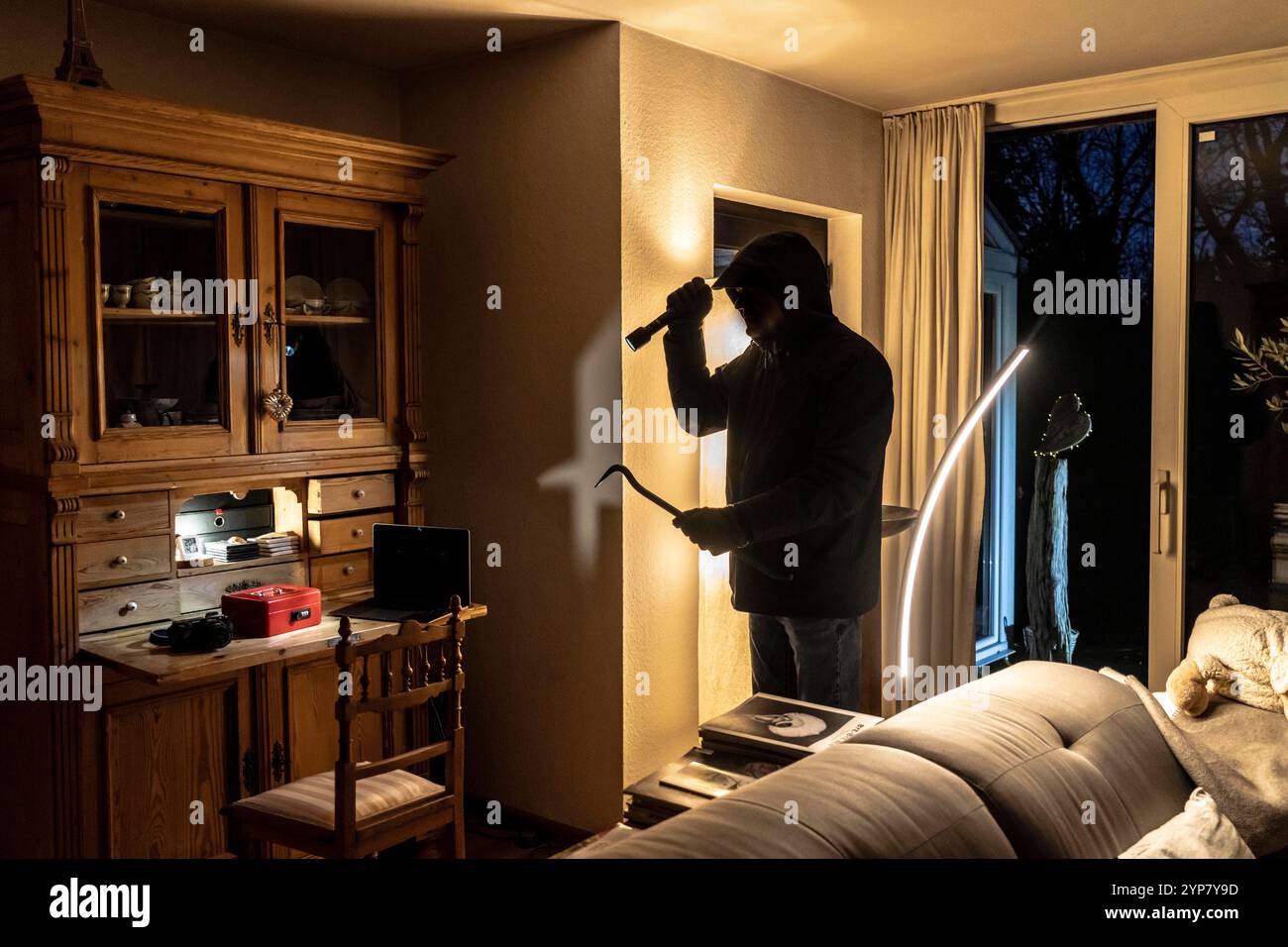 Image symbolique d'un cambriolage, l'auteur est entré par effraction dans un appartement du côté du jardin et est à la recherche de butin, caisse, objets de valeur, argent, techn Banque D'Images