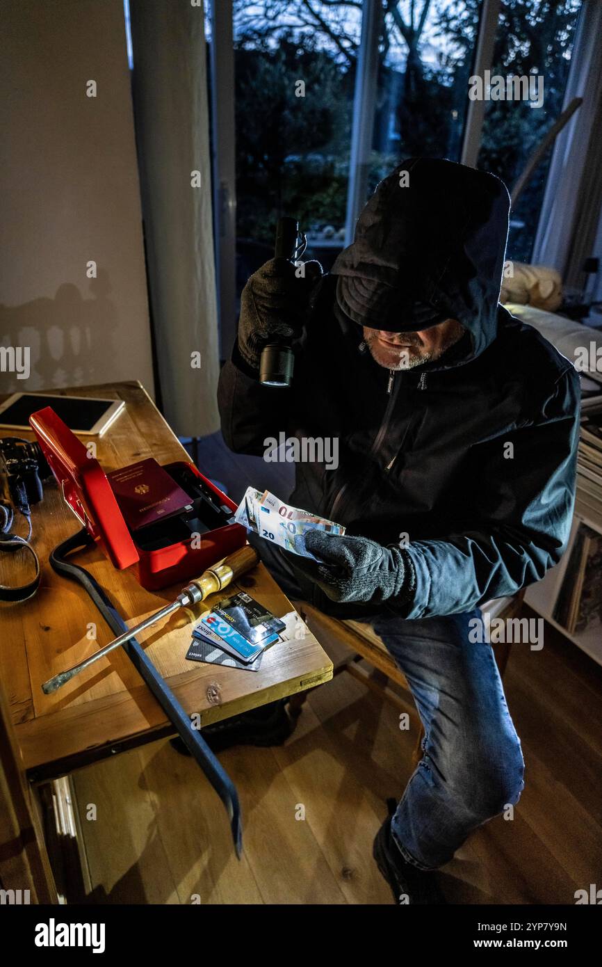 Image symbolique d'un cambriolage, l'auteur est entré par effraction dans un appartement du côté du jardin et est à la recherche de butin, ouvre une caisse, trouve val Banque D'Images