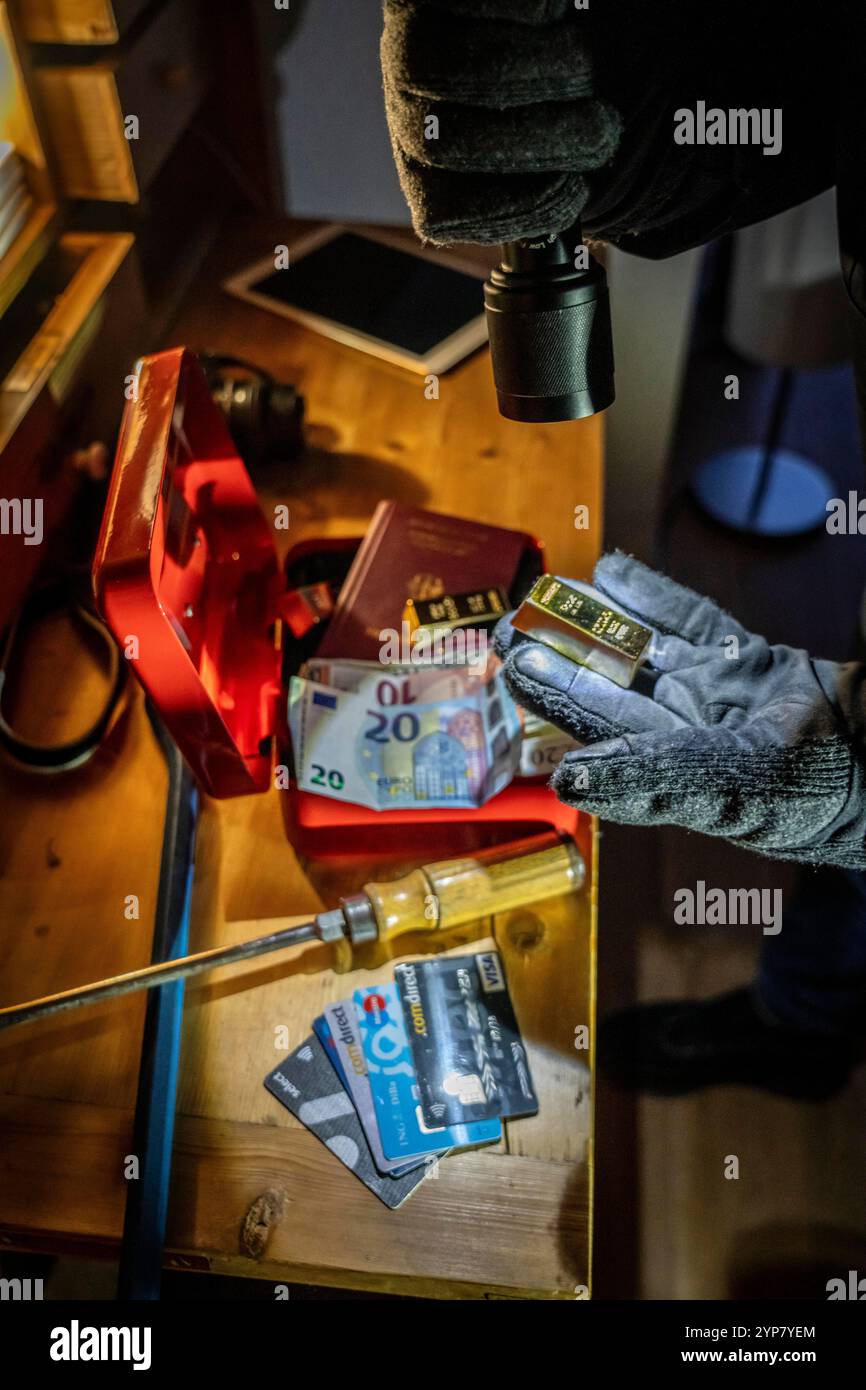 Image symbolique d'un cambriolage, l'auteur est entré par effraction dans un appartement du côté du jardin et est à la recherche de butin, ouvre une caisse, trouve val Banque D'Images