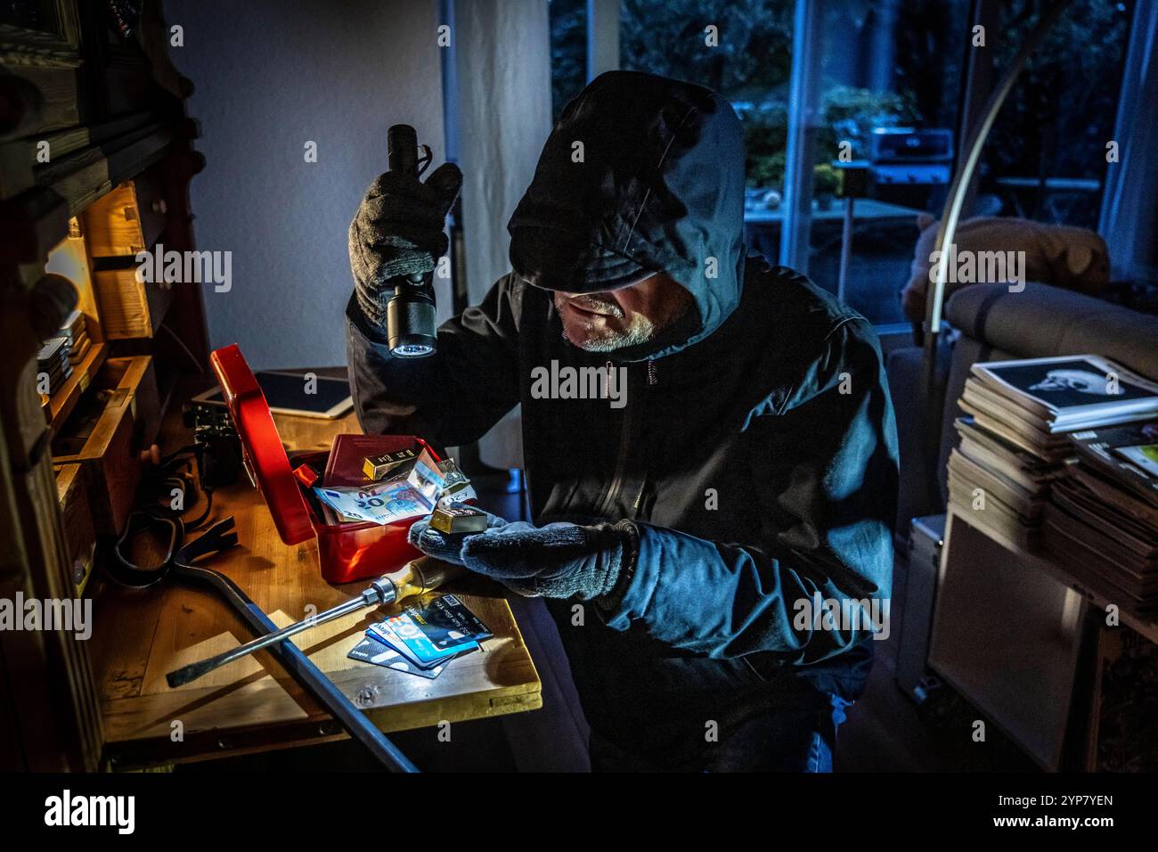 Image symbolique d'un cambriolage, l'auteur est entré par effraction dans un appartement du côté du jardin et est à la recherche de butin, ouvre une caisse, trouve val Banque D'Images