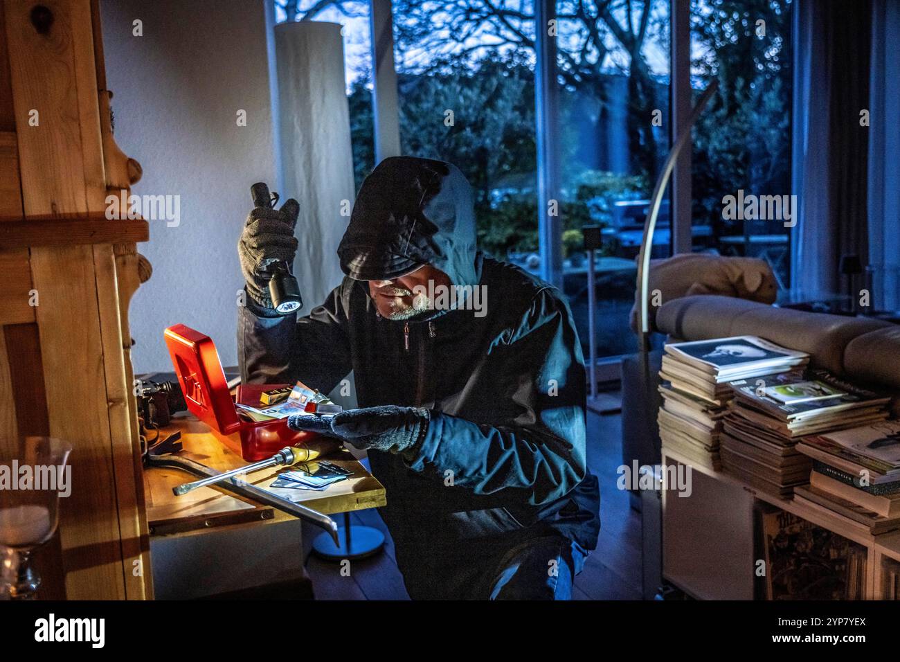 Image symbolique d'un cambriolage, l'auteur est entré par effraction dans un appartement du côté du jardin et est à la recherche de butin, ouvre une caisse, trouve val Banque D'Images
