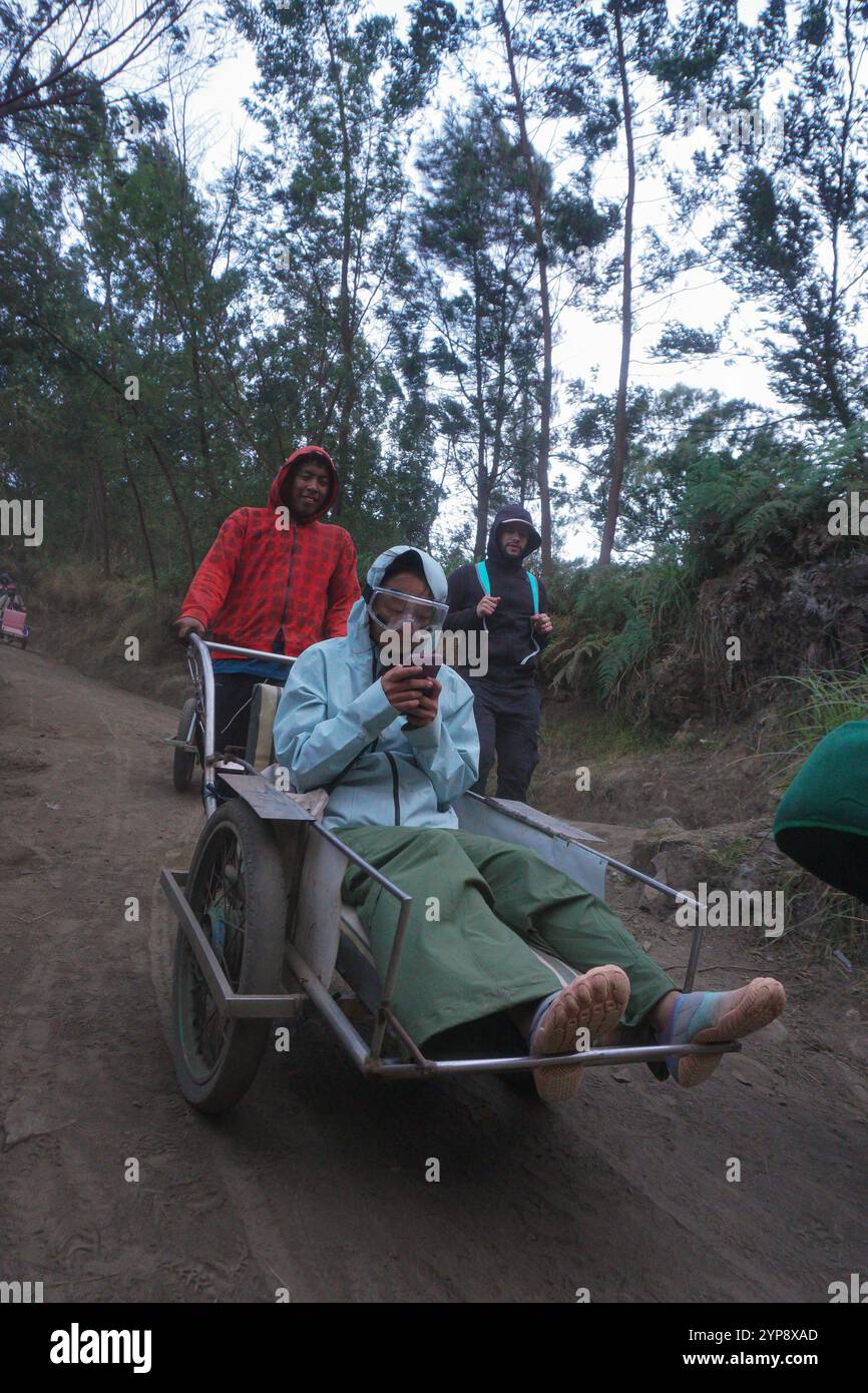 Un ouvrier transportant un touriste du mont Ijen en utilisant une brouette auto-fabriquée Banque D'Images