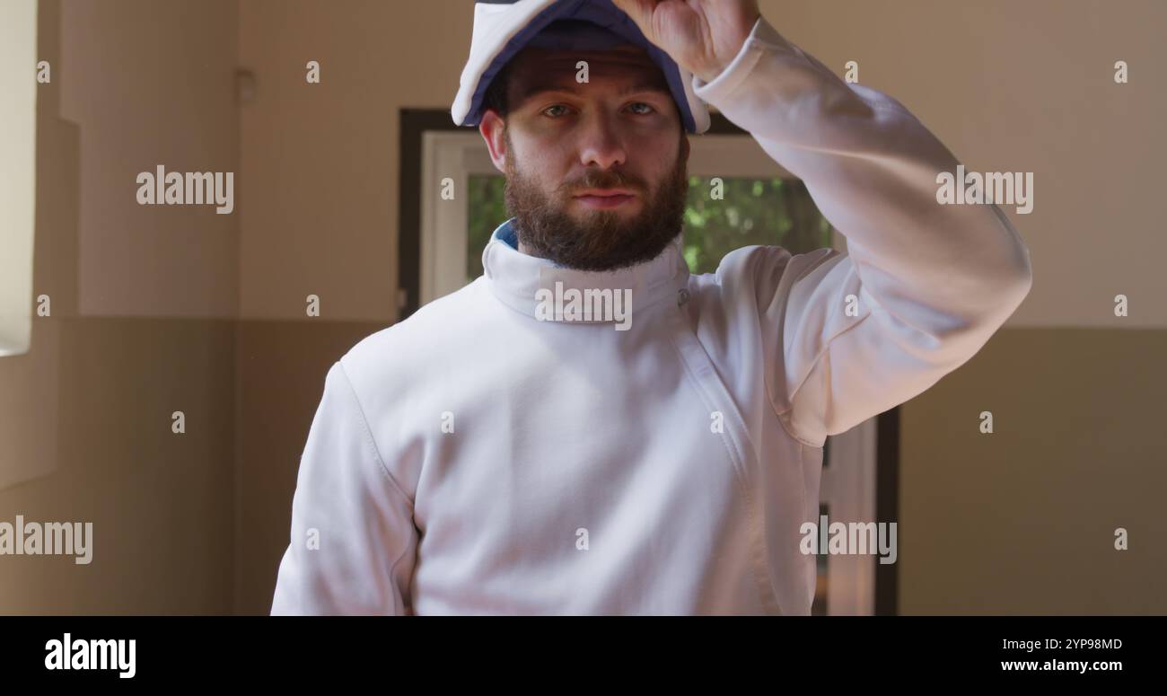 Portrait d'un athlète d'escrimeur masculin caucasien concentré confiant lors d'un entraînement d'escrime dans un gymnase, St Banque D'Images